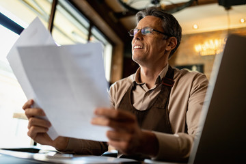 Below view of happy barista working on paperwork in a pub.