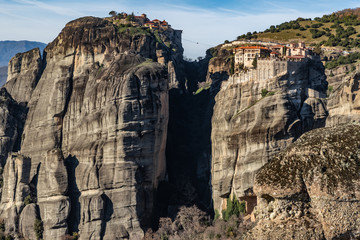 Fototapeta na wymiar Kalambaka, Greece, Aerial view of monastery Varlaam and breathtaking pictures of valley and landmark canyon of Meteora at sunset, Cradle on a ropeway, shadows, twisted road, bridge