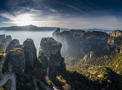 Aerial view of monastery Trinity and breathtaking pictures of valley and landmark canyon of Meteora at sunset, Kalambaka, Greece, shadows, twisted road, bridge, Mountains as columns