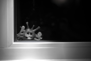 coronavirus comes to our house: A funny monster virus looks through a window, lowering color