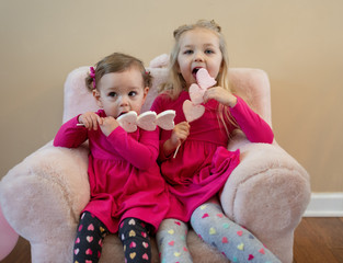 Two little girls having heart shaped pops for a sweet treat