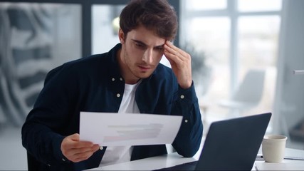 Focused business man reading documents. Serious guy checking data in papers
