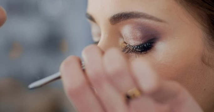 makeup artist imposes false eyelashes to model in beauty salon