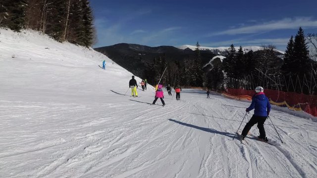 First-person view on Skiers and Snowboarders Slide Down on Ski Slope at Ski Resort