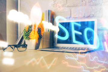 Multi exposure of table with computer and seo drawing hologram. Search optimization concept.