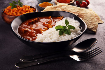 Chicken tikka masala spicy curry meat food in pot with rice and naan bread. indian food on table