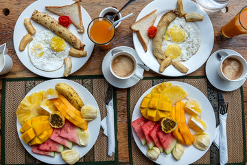 Tropical breakfast of fruit, coffee and scrambled eggs and banana pancake for two on the beach near sea