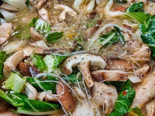 Fototapeta na wymiar cooking pot filled with mushrooms, bok chok, rice noodles, and other healthy foods