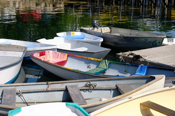 Fototapeta na wymiar Docked small rowboats and skiffs tied together on a calm and peaceful Coastal Maine dock and Harbor