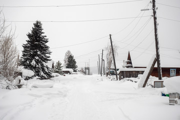 Fototapeta premium Winter landscape. Exterior view of wooden houses covered with snow in Russian village located in Siberia. Russia.