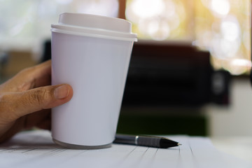 Obraz na płótnie Canvas Paper coffee cup mock-up. Businessman holding white cardboard cup for logo with document paperwork on meeting. Concept of business people working in office and save world. Mockup for word