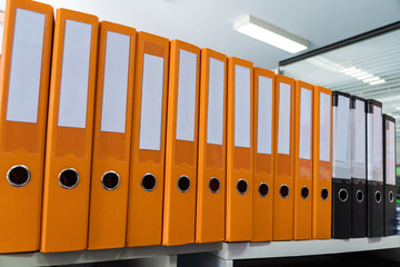 Documents Binder Paper and note with blank label on shelf in archive orange Files folder on office,...