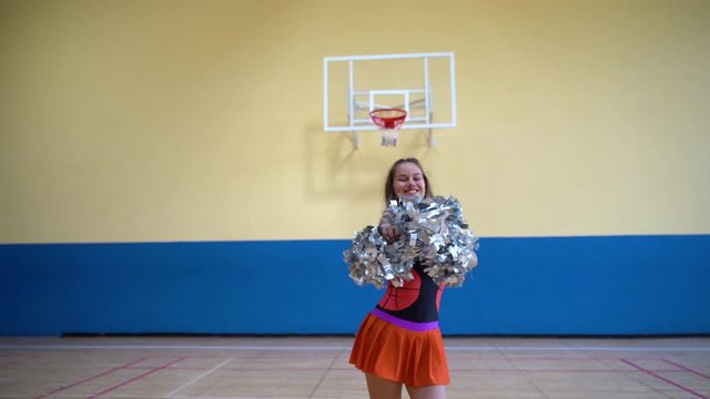 Young girl in cheerleader uniform with pom poms support high school sport team