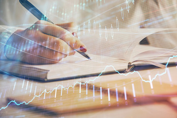 Multi exposure of woman's hands making notes with forex graph hologram. Concept stock market...