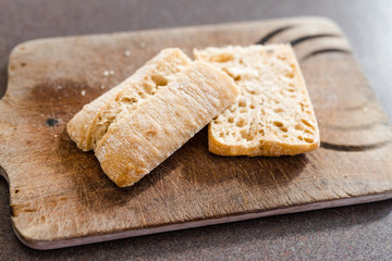 ciabatta bread cut in half on cutting board with knife next to it