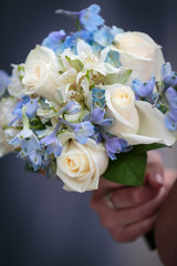 Bouquet of white roses and blue flowers hand held