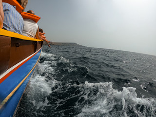 Obraz premium Residents and tourists visit the coast of Malta in a tourist boat, protected with life jackets. Theme park.