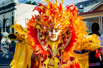 person in flamboyant costume poses for photo on city strreet at dominican carnival