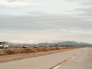 Fototapeta na wymiar Mojave, United States - December 02, 2019: Car traffic by road in the Mojave Desert.
