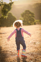 Fototapeta premium Cute little girl wearing overalls and gumboots