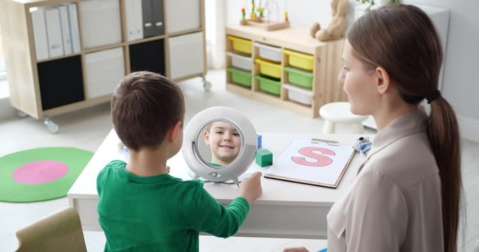 Speech therapist working with little boy in office