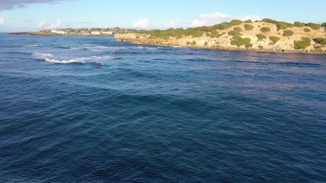 Low elevation arial video chasing, following, waves as they approach the rocky coast and finally break, Shipwreck Beach #2, Poipu, Koloa, Kauai, Hawaii