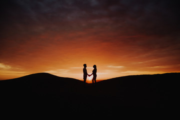  romantic couple in backlight jumping at sunset