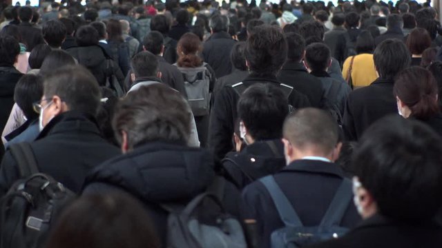 SHINAGAWA, TOKYO, JAPAN - MARCH 2020 : Crowd of people walking down the street in busy morning rush hour. Many commuters going to work. Japanese business, job and lifestyle concept. Slow motion shot.