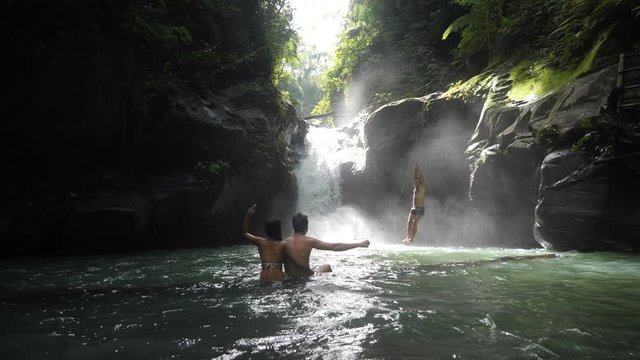 Tourist couple cheering thier friends to jump in the waterfalls.