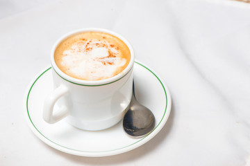 Cafe en taza blanca con linea verde y mantel blanco