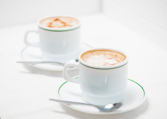Cafe en taza blanca con linea verde y mantel blanco