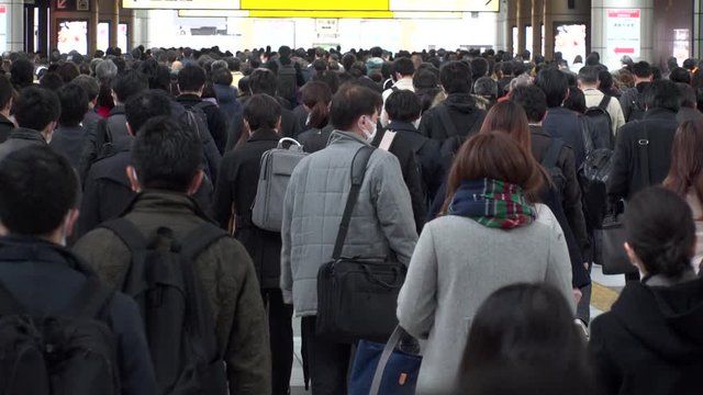 SHINAGAWA, TOKYO, JAPAN - MARCH 2020 : Crowd of people walking down the street in busy morning rush hour. Many commuters going to work. Japanese business, job and lifestyle concept. Slow motion shot.