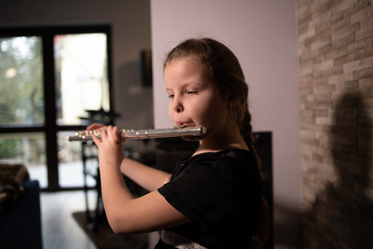 Little Girl Playing The Flute At Home