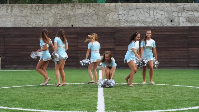 Athletic girls in cheerleader uniform with pom poms making acrobatic elements together