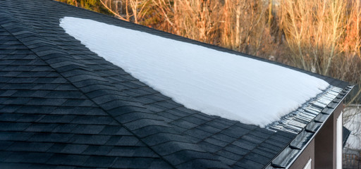 Snow melting on shingled roof with eavestrough drain