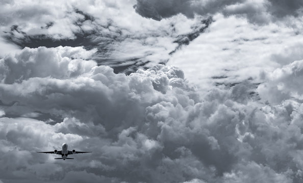 Airplane flying on dark sky and white fluffy cloud. Commercial airline with dream destinations concept. Aviation business crisis concept. Failed summer vacation flight. Air transportation. Sad travel.