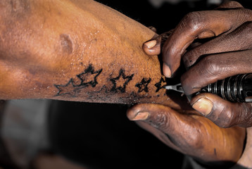 simple star tattoo,Tattoo artist doing tattoo in tatoo shop .Master makes tattoo in  outdoor