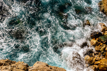 Obraz premium A close-up shot of the Mediterranean Sea turquoise water and powerful waves beating against the rocks on the coast