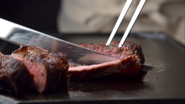 cutting beef steak on iron plate