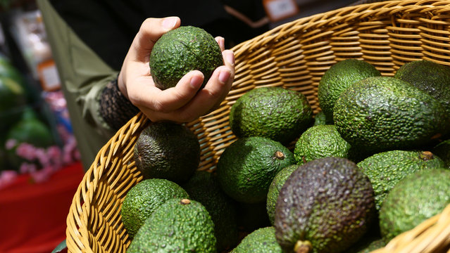 Close Up Of Women Hand Buying Avocado From Shop 