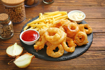 Crispy onion rings, french fries and sauces on table