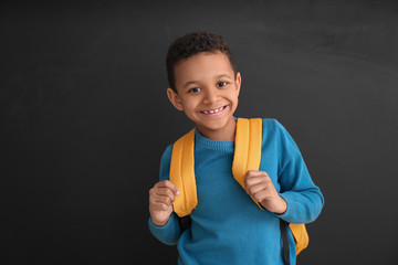 Cute African-American schoolboy near blackboard in classroom
