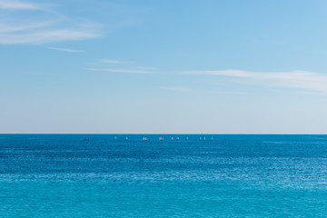 The panoramic view of the turquoise water of the Mediterranean Sea and the white boats in the distance on the horizon on a sunny day (Provence Côte d'Azur, France)