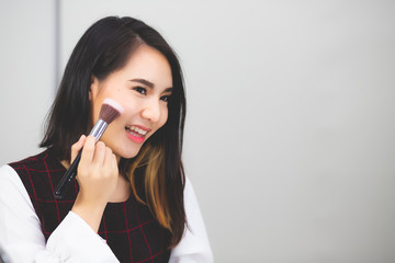 Beautiful Asian women, Thai people are using a blush brush with smiles and happiness.