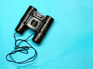 Binoculars. Background binoculars top view of copyspace. Binoculars with a rope close- up on a blue background. Magnifying binoculars. Zoom. Template.