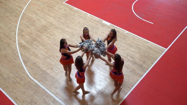 Proud cheer leaders girls in uniform with pom poms support high school sport team
