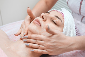 Beautician doctor cleans the skin of a young woman