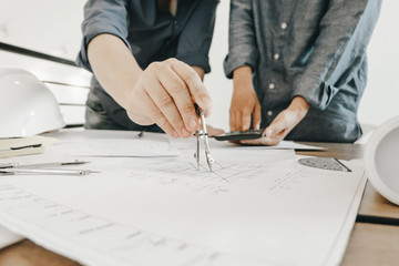 engineers pointing to building on blueprint and using laptop to drawing design building Project in...