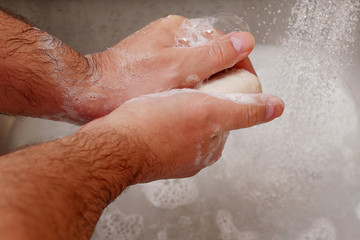 Fototapeta premium man washing hands with soap in sink with running water
