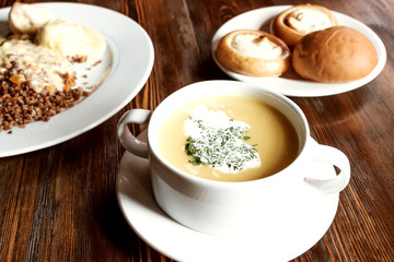 a cup of soup and a plate with a second course on the table